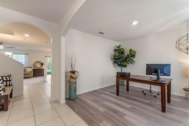 office area featuring arched walkways, visible vents, light wood-style floors, ceiling fan, and baseboards