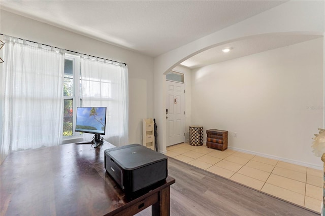 interior space with baseboards, arched walkways, and wood finished floors