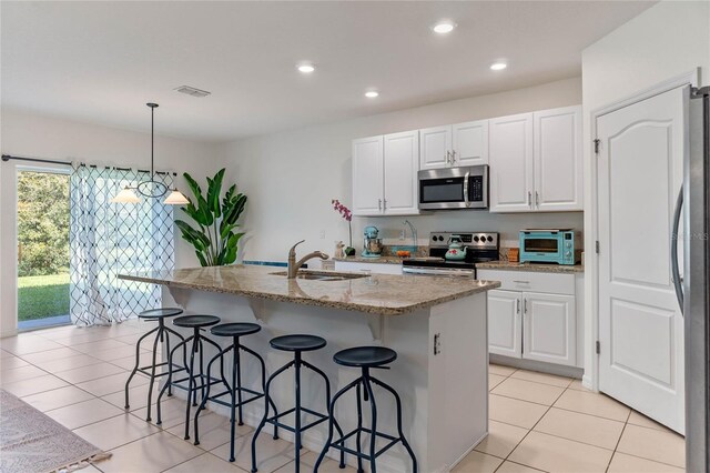 kitchen with a breakfast bar area, stainless steel appliances, visible vents, white cabinets, and a sink