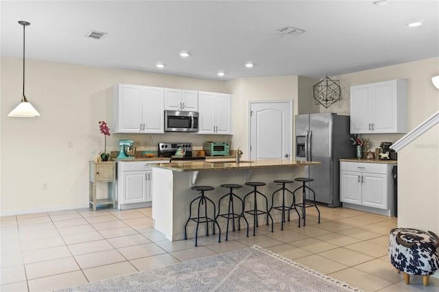 kitchen with light tile patterned floors, visible vents, a breakfast bar, stainless steel appliances, and white cabinetry