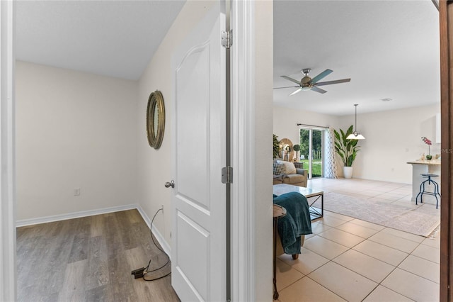 hallway with tile patterned flooring, visible vents, and baseboards