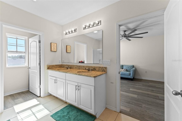 ensuite bathroom with double vanity, a ceiling fan, a sink, and tile patterned floors