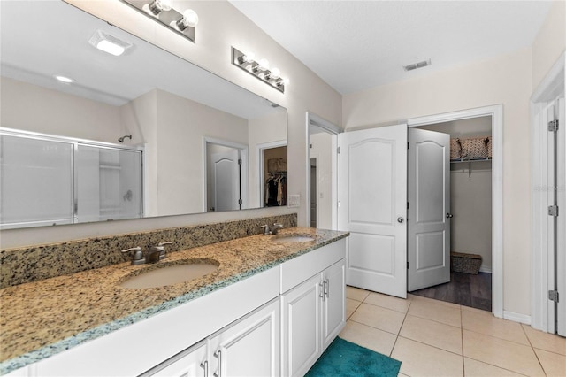 full bath featuring tile patterned flooring, a spacious closet, an enclosed shower, and a sink