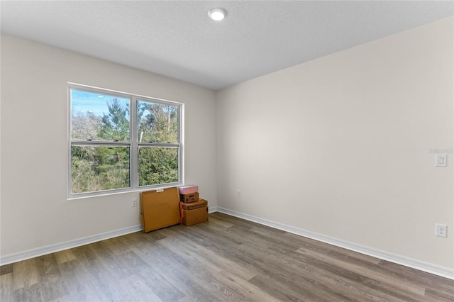 spare room featuring a textured ceiling, baseboards, and wood finished floors