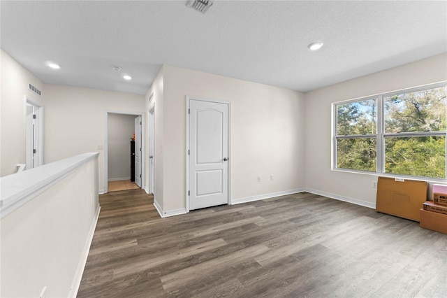 unfurnished room featuring recessed lighting, wood finished floors, visible vents, and baseboards