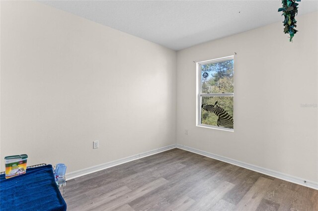 spare room featuring a textured ceiling, baseboards, and wood finished floors