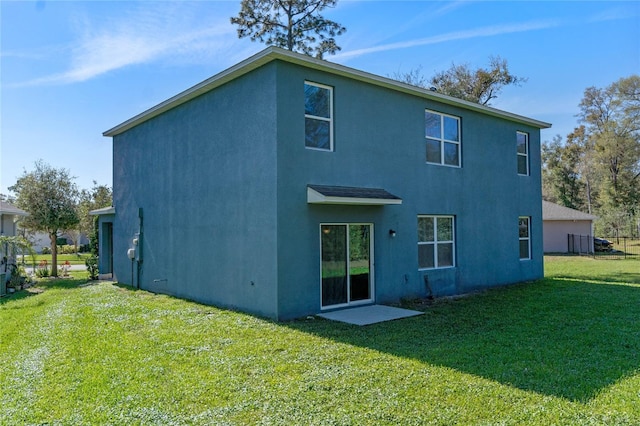 back of house featuring a lawn and stucco siding