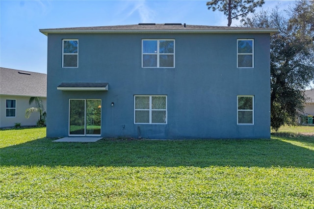 rear view of house featuring a yard and stucco siding