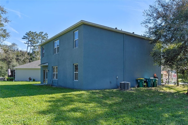 view of home's exterior featuring central air condition unit, a lawn, and stucco siding