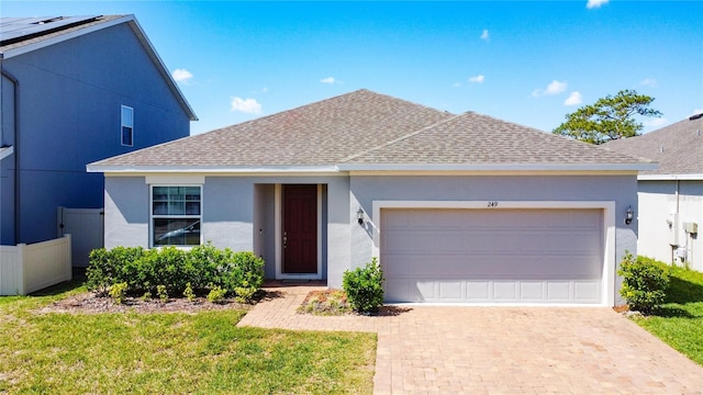 single story home with a garage, a shingled roof, decorative driveway, stucco siding, and a front yard