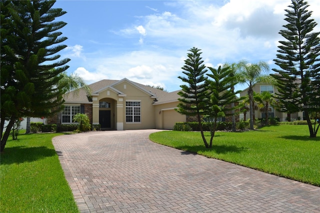 view of front of home featuring a garage, stone siding, decorative driveway, a front lawn, and stucco siding