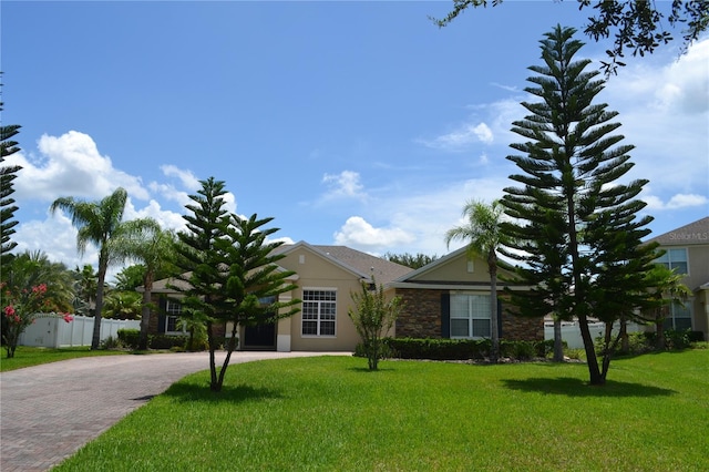 view of front facade with a front lawn, decorative driveway, and fence