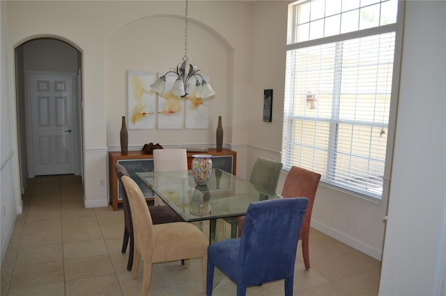 dining space with arched walkways, light tile patterned floors, plenty of natural light, and an inviting chandelier