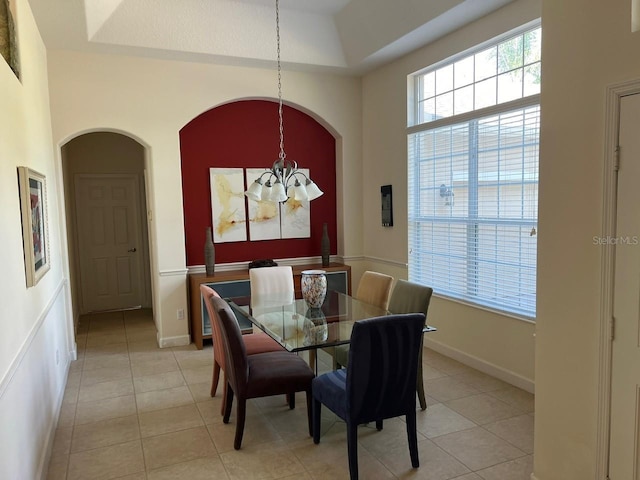 dining room with a towering ceiling, light tile patterned floors, baseboards, and a notable chandelier