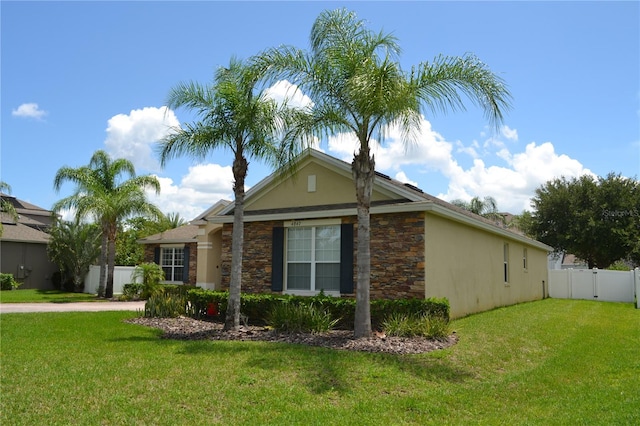 view of side of home featuring stone siding, a yard, fence, and stucco siding