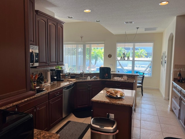 kitchen featuring visible vents, dishwasher, stainless steel microwave, a peninsula, and a sink