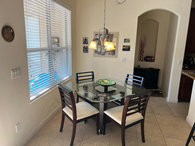 dining area featuring light tile patterned floors, baseboards, and an inviting chandelier