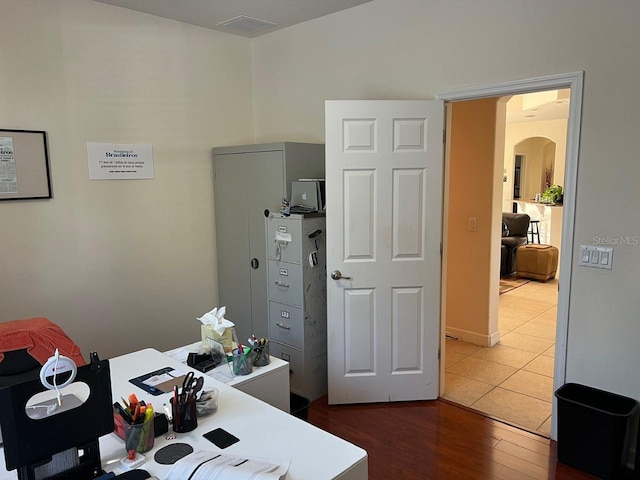 office featuring arched walkways and wood finished floors