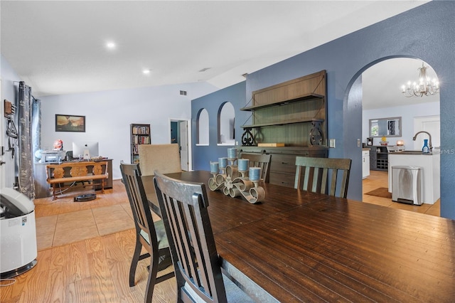 dining room with light wood-style flooring, visible vents, arched walkways, and vaulted ceiling