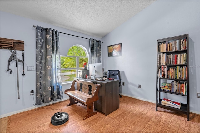 office featuring lofted ceiling, a textured ceiling, baseboards, and wood finished floors