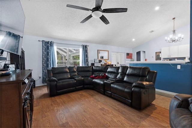 living room with ceiling fan with notable chandelier, vaulted ceiling, a textured ceiling, and wood finished floors