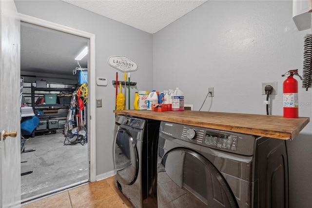 washroom with laundry area, light tile patterned floors, separate washer and dryer, and a textured ceiling