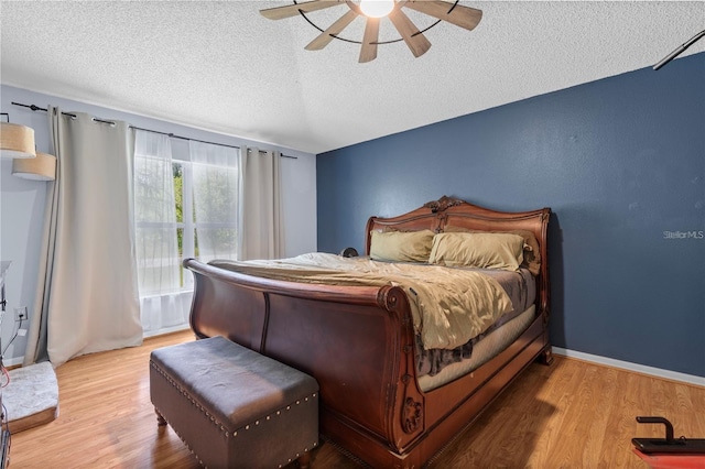 bedroom with baseboards, ceiling fan, wood finished floors, access to exterior, and a textured ceiling