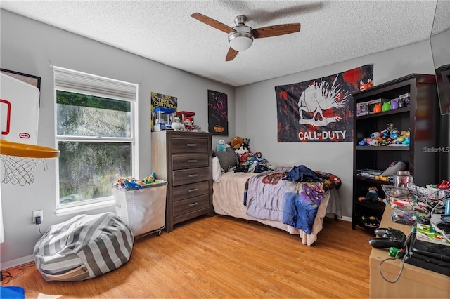 bedroom with a textured ceiling, light wood-type flooring, and a ceiling fan