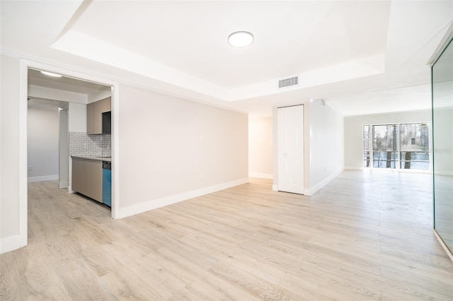 empty room featuring a tray ceiling, visible vents, and light wood-style flooring