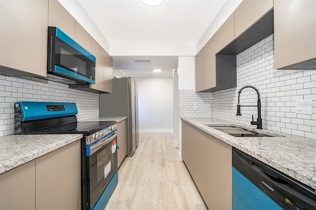 kitchen featuring light stone counters, a sink, stainless steel range with electric cooktop, dishwasher, and light wood finished floors