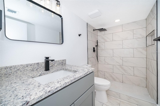 full bath with marble finish floor, visible vents, toilet, a tile shower, and vanity