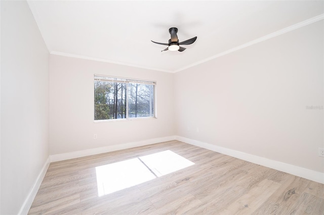 empty room with a ceiling fan, light wood-type flooring, crown molding, and baseboards