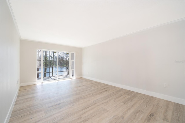 spare room with light wood-type flooring, a water view, baseboards, and crown molding