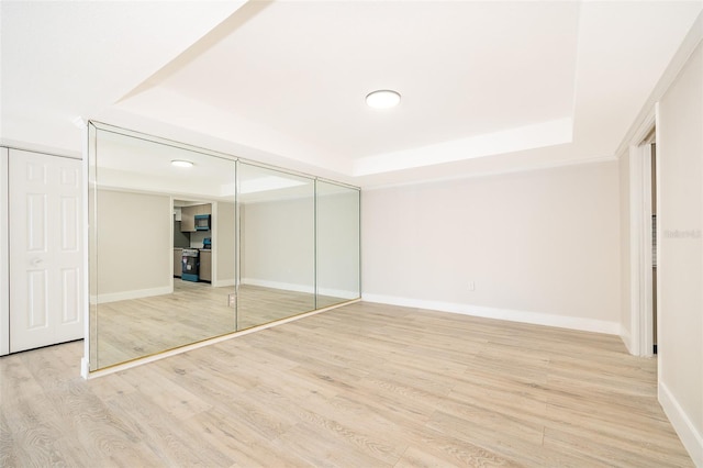 unfurnished bedroom featuring a raised ceiling, baseboards, and wood finished floors