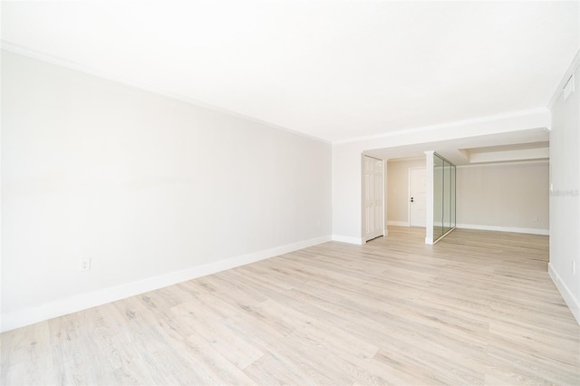 empty room featuring ornamental molding, light wood-type flooring, and baseboards