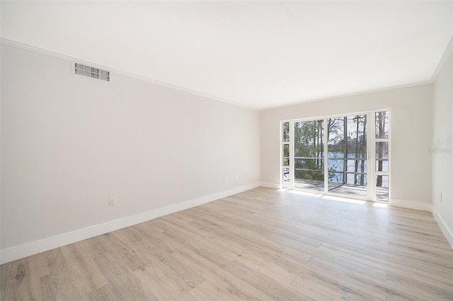 spare room with baseboards, visible vents, crown molding, and light wood finished floors