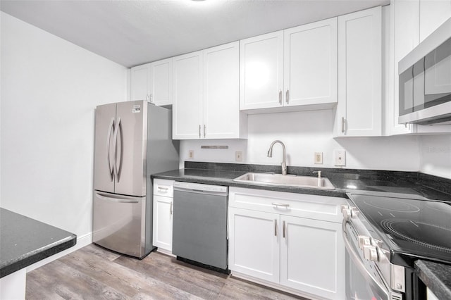 kitchen featuring appliances with stainless steel finishes, white cabinetry, and a sink