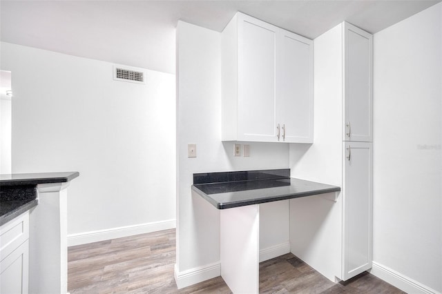 kitchen featuring white cabinetry, dark countertops, visible vents, and light wood finished floors