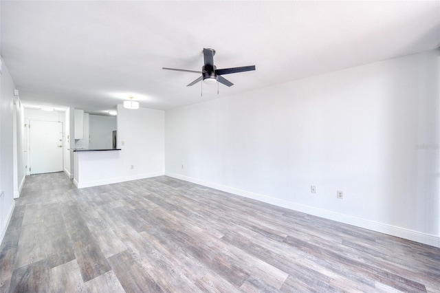 empty room featuring baseboards, light wood-type flooring, and ceiling fan