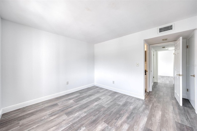 empty room with visible vents, baseboards, and wood finished floors