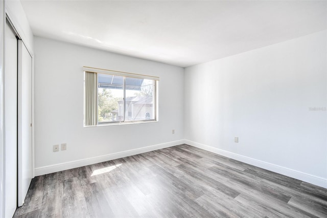 unfurnished bedroom with a closet, baseboards, and wood finished floors