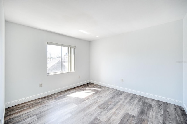 unfurnished room with baseboards and wood finished floors