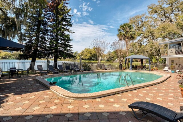 community pool with a gazebo, fence, and a patio area