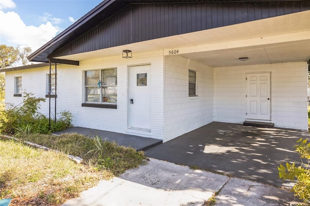 property entrance featuring an attached carport and brick siding