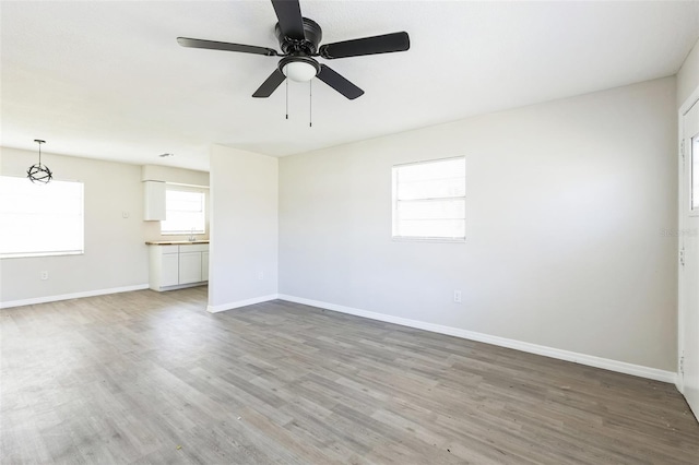 empty room with ceiling fan, baseboards, and wood finished floors