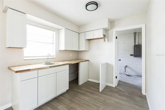 kitchen featuring white cabinets, electric panel, a sink, and wooden counters