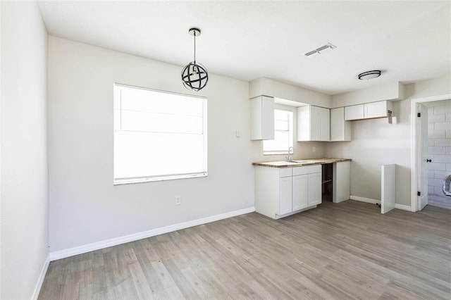 kitchen with light wood-type flooring, visible vents, and white cabinetry