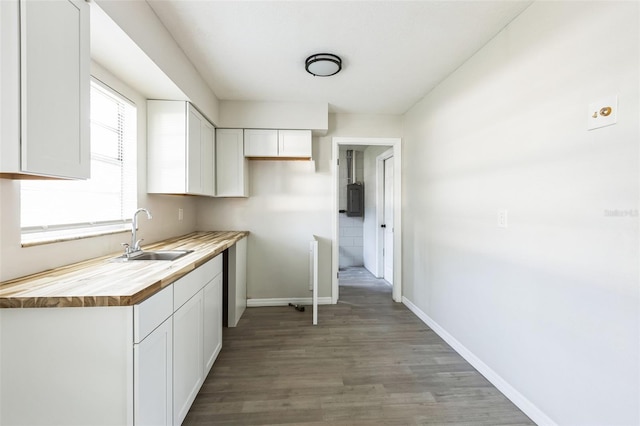 kitchen featuring baseboards, butcher block counters, light wood-style flooring, white cabinetry, and a sink