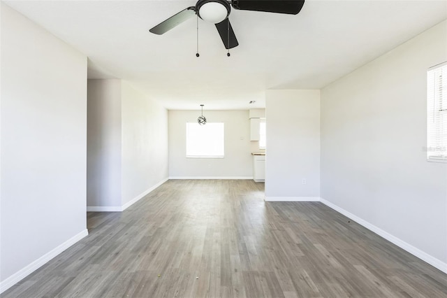 empty room featuring ceiling fan, wood finished floors, and baseboards