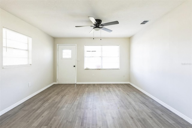 spare room featuring ceiling fan, wood finished floors, visible vents, and baseboards